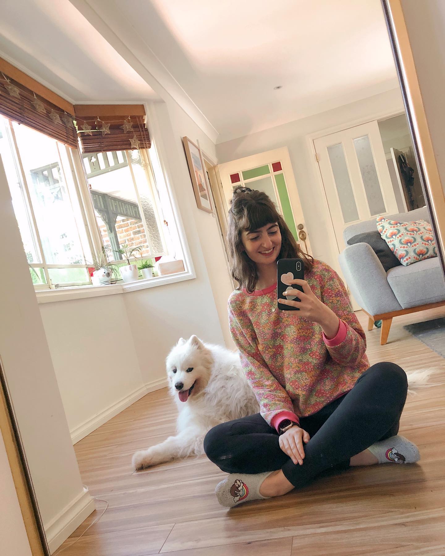 Taryn sitting on the floor wearing the first jumper she ever sewed. Lexi the samoyed dog is laying on the floor behind her.